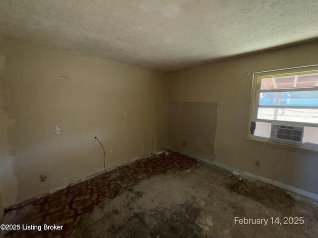 empty room featuring baseboards, cooling unit, and a textured ceiling