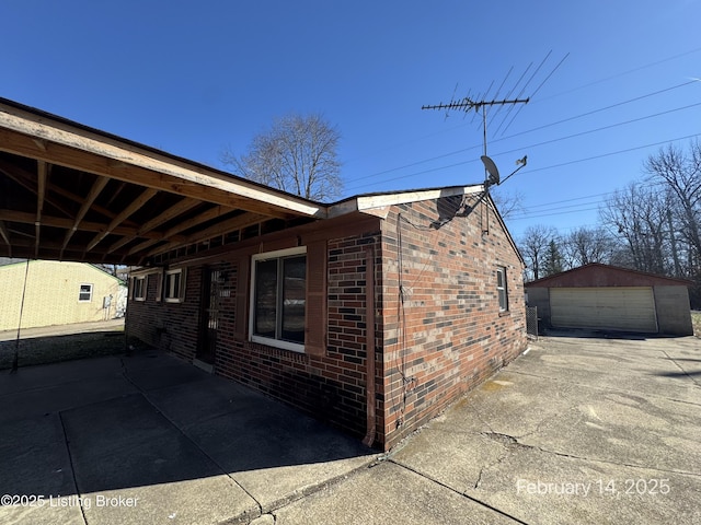 view of home's exterior featuring a garage, concrete driveway, brick siding, and an outdoor structure