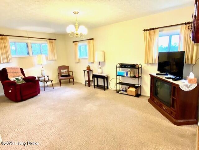 sitting room with a healthy amount of sunlight, an inviting chandelier, and carpet flooring