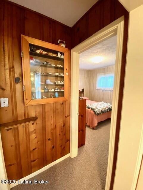 hall featuring carpet and wooden walls