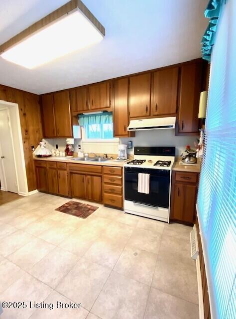 kitchen featuring range with gas stovetop, range hood, light countertops, and a sink