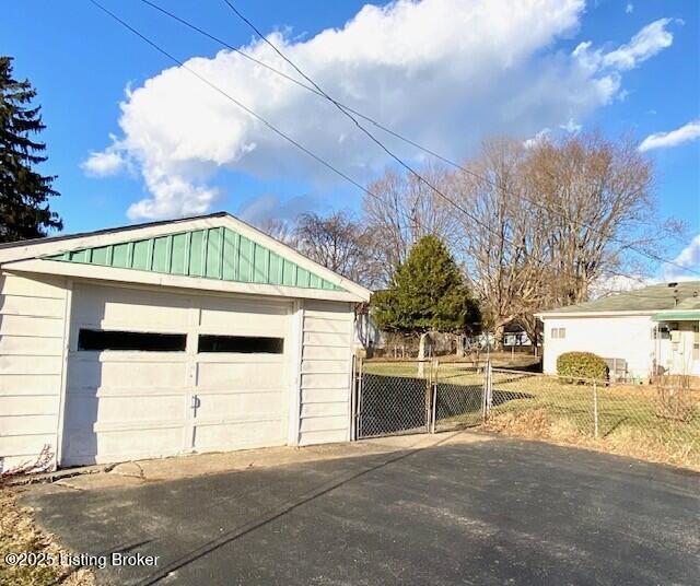 detached garage featuring fence and concrete driveway