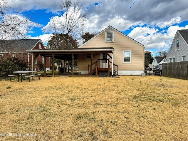 back of property featuring a carport, fence, and a lawn