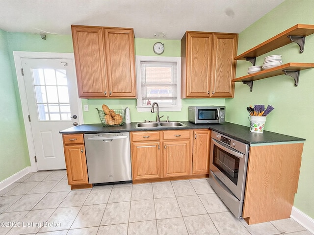 kitchen featuring dark countertops, appliances with stainless steel finishes, open shelves, and a sink