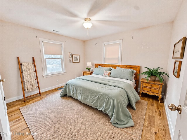 bedroom featuring baseboards, visible vents, and light wood finished floors