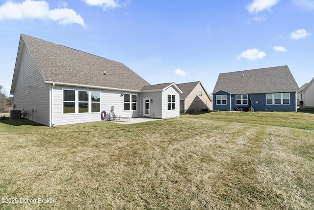 rear view of house featuring a patio, a yard, central AC, and roof with shingles