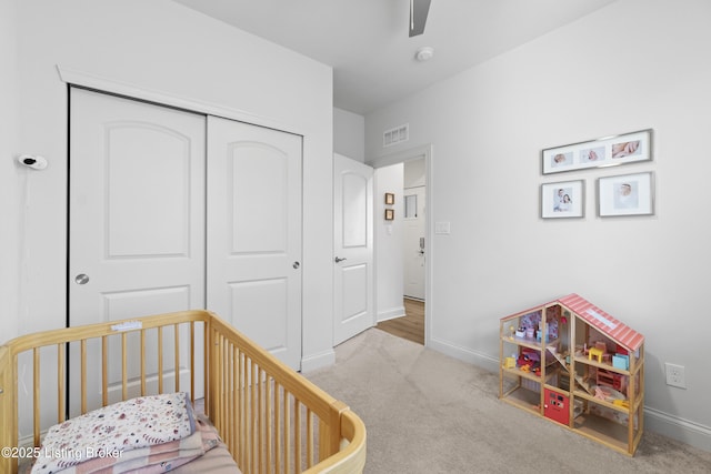 bedroom featuring a closet, visible vents, carpet flooring, a nursery area, and baseboards