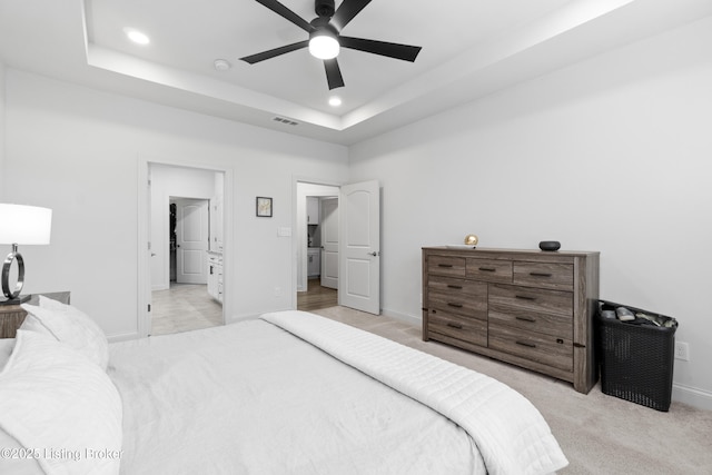 bedroom with a tray ceiling, visible vents, light carpet, and recessed lighting