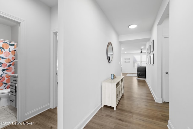 corridor with light wood-style floors and baseboards