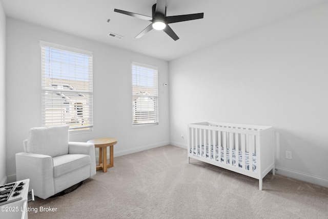 bedroom with carpet, visible vents, a ceiling fan, a crib, and baseboards