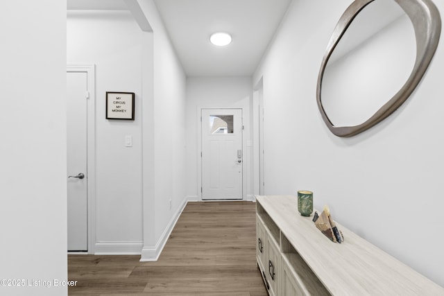 corridor with light wood finished floors and baseboards