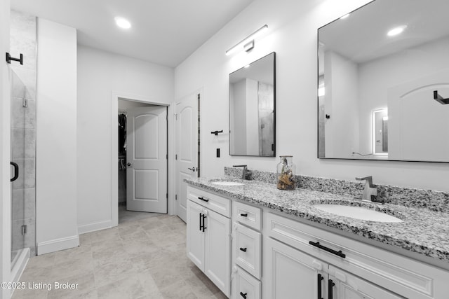 full bathroom featuring a stall shower, a walk in closet, a sink, and double vanity