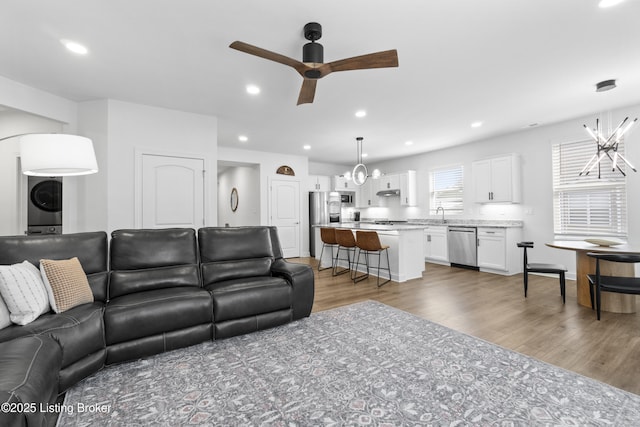 living room with ceiling fan with notable chandelier, wood finished floors, and recessed lighting