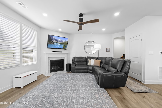 living area with recessed lighting, visible vents, a fireplace, and wood finished floors