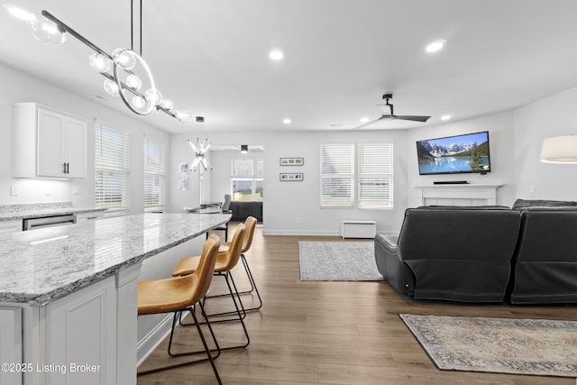 kitchen featuring white cabinets, ceiling fan, open floor plan, and wood finished floors