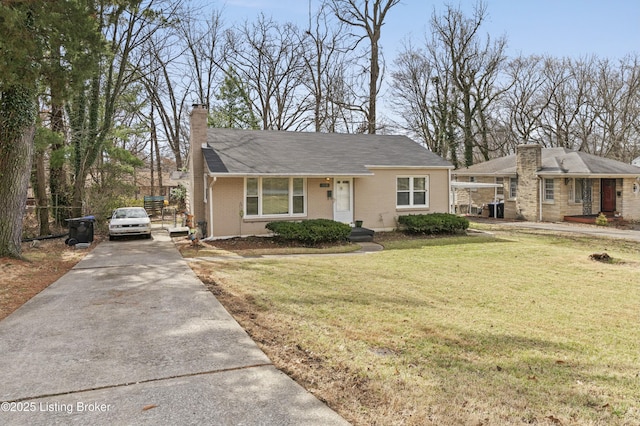 view of front facade with concrete driveway, a front lawn, a chimney, and brick siding