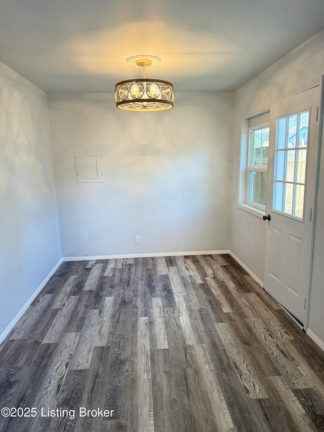 unfurnished dining area with dark wood-style floors and baseboards