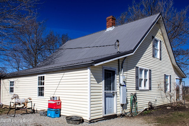 rear view of house with metal roof and a chimney