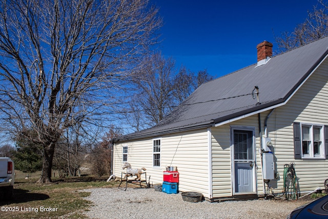 view of side of property with metal roof and a chimney