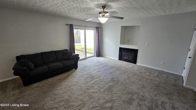 living room with carpet, baseboards, a textured ceiling, and a glass covered fireplace