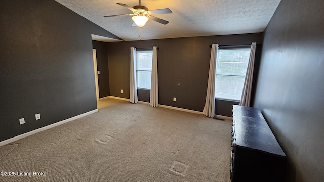 empty room featuring lofted ceiling, ceiling fan, baseboards, and a textured ceiling