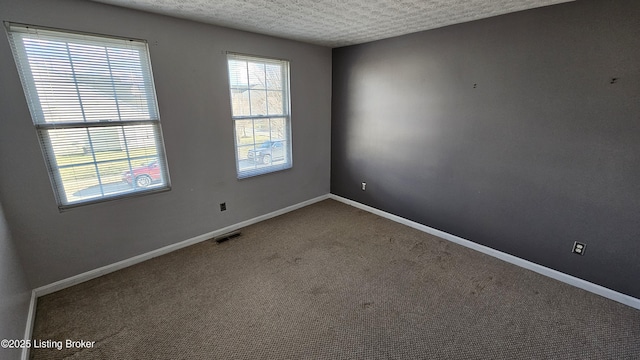 carpeted empty room with visible vents, baseboards, and a textured ceiling