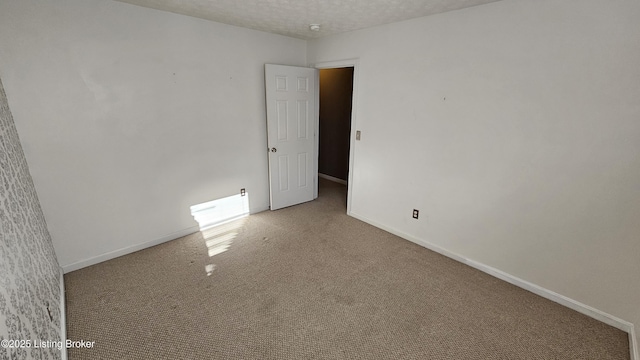 empty room with a textured ceiling, carpet, and baseboards