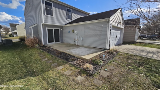 rear view of house featuring a garage, concrete driveway, central AC, and a yard