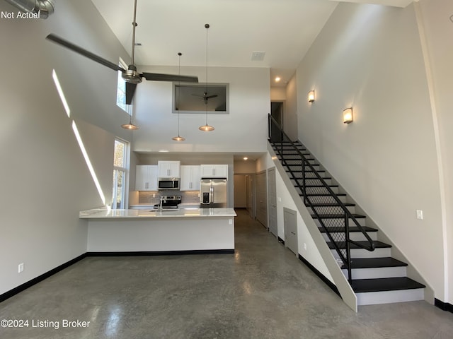 interior space featuring finished concrete floors, visible vents, a towering ceiling, and baseboards