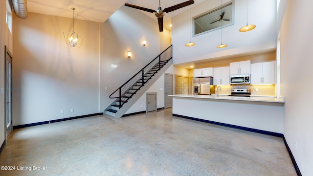 unfurnished living room with finished concrete flooring, baseboards, a towering ceiling, stairs, and a sink