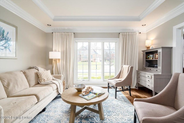 living room with ornamental molding, a tray ceiling, and wood finished floors