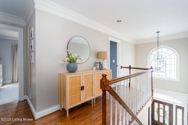 corridor featuring ornamental molding, dark wood finished floors, an upstairs landing, and baseboards