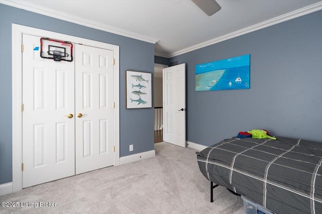 carpeted bedroom with ornamental molding, a closet, ceiling fan, and baseboards