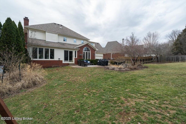 back of house with a yard, a patio area, fence, and brick siding