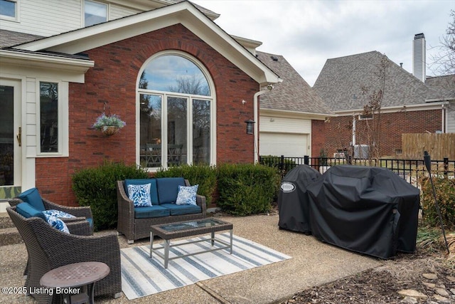 view of patio featuring area for grilling, an attached garage, fence, and an outdoor living space