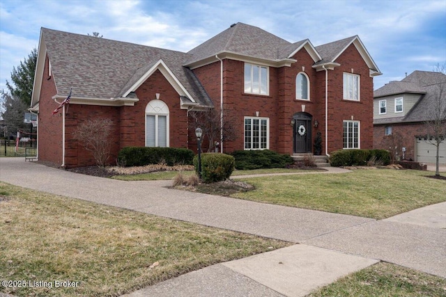 view of front facade with a shingled roof, brick siding, and a front lawn