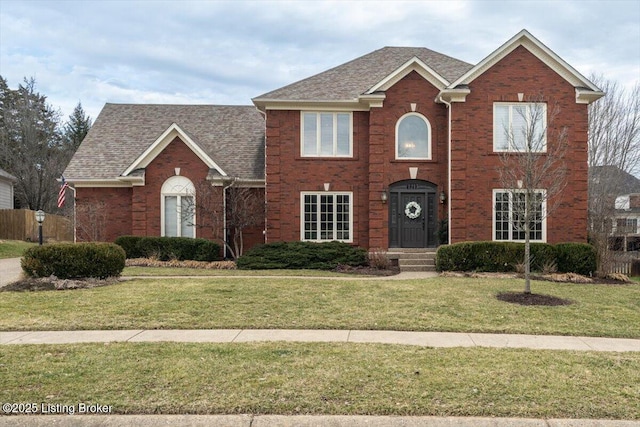 view of front of home featuring a shingled roof, brick siding, and a front lawn