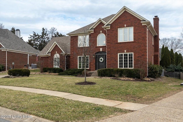 view of front of home with central AC unit, brick siding, fence, a front lawn, and a chimney