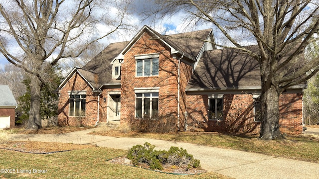 view of front of home with concrete driveway, brick siding, and roof with shingles