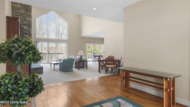 interior space featuring a high ceiling, baseboards, wood finished floors, and recessed lighting