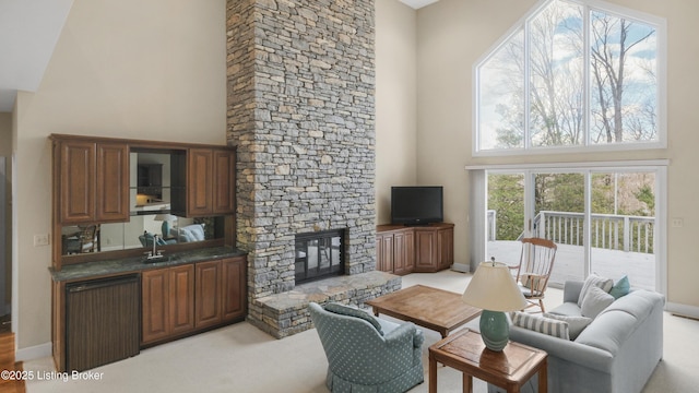 living area featuring light carpet, a fireplace, a towering ceiling, and baseboards