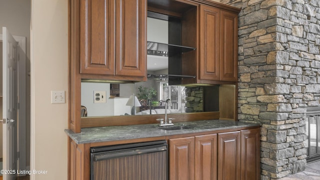 kitchen with brown cabinetry, a sink, and dishwashing machine