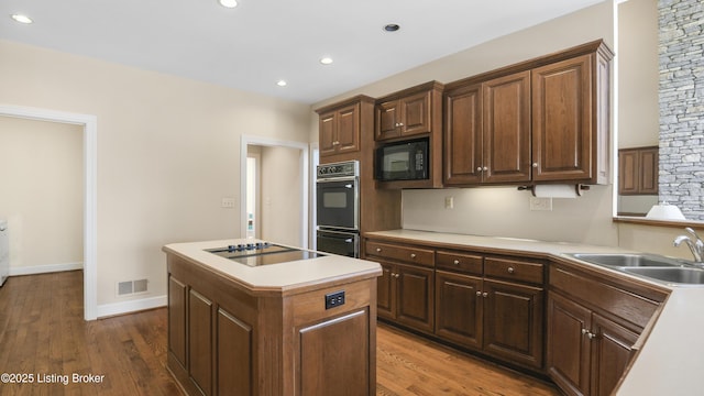 kitchen with visible vents, a sink, black appliances, and wood finished floors