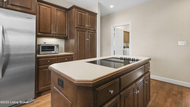 kitchen featuring light wood-style floors, a toaster, stainless steel fridge, and black electric stovetop