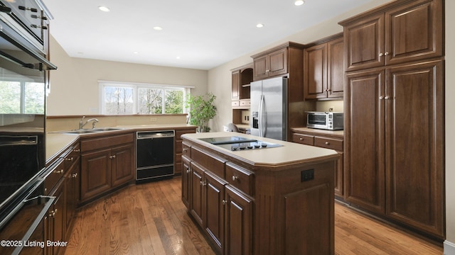 kitchen with black appliances, dark wood-type flooring, a kitchen island, and a sink