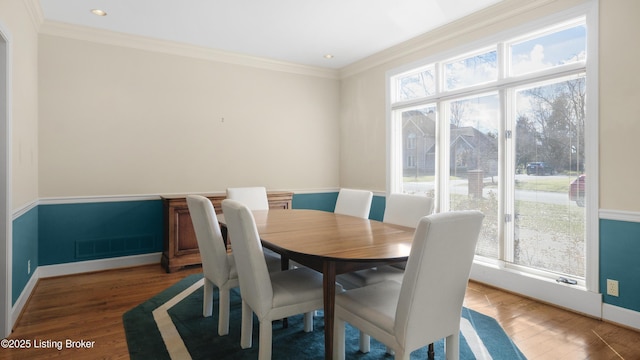 dining area with ornamental molding, wood finished floors, visible vents, and baseboards