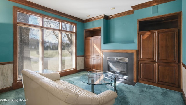 carpeted living room with a fireplace with flush hearth, wainscoting, and ornamental molding