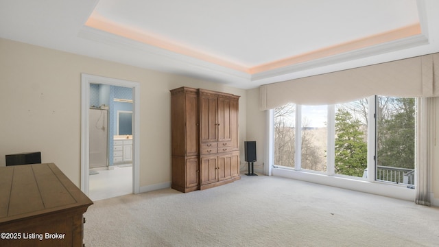 unfurnished bedroom featuring light carpet, ensuite bath, and a raised ceiling