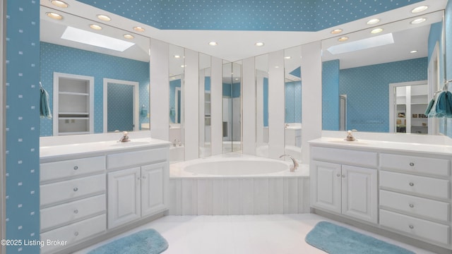 full bathroom featuring a skylight, a garden tub, vanity, and wallpapered walls