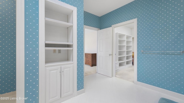 unfurnished bedroom with a spacious closet, tile patterned floors, and wallpapered walls